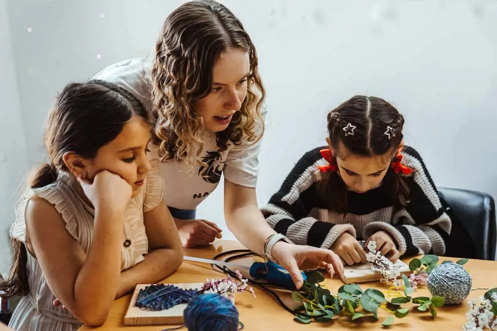 Kindern Chancen geben – Zwei Mädchen basteln mit einer Betreuerin in einer Kindertagesstätte in der Republik Moldau – Teil eines Projekts zur Stärkung von Familien und Kindern.