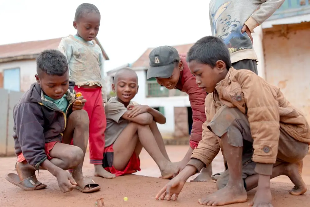 Kindern Chancen geben – Kinder spielen auf einem staubigen Platz in Madagaskar – Kind gerechte Räume schaffen. Chancen auf gesunde Entwicklung geben.