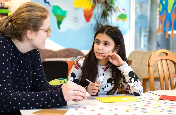 Soziale Integration – Auf dem Bild sind eine Sozialarbeiterin und ein Mädchen bei WiLLmA zu sehen bei intensiver Hausaufgabenbetreuung.