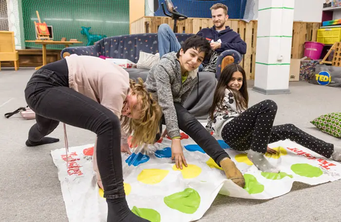 Soziale Integration – Auf dem Bild sind fröhliche Kinder zu sehen, die gemeinsam Twister spielen.